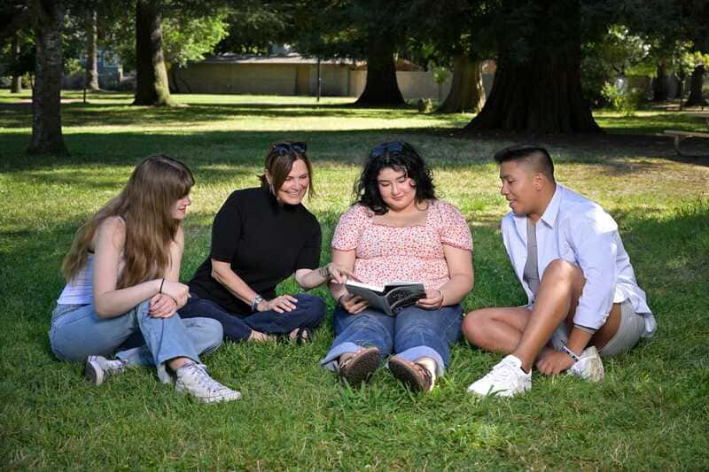 people sitting around on grass looking at a book
